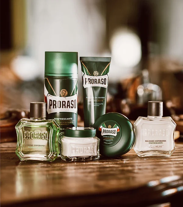 Proraso pianka do golenia zielona - kompletna linia produktów w opakowaniu, widok zestawu na drewnianym blacie z rozmytym tłem