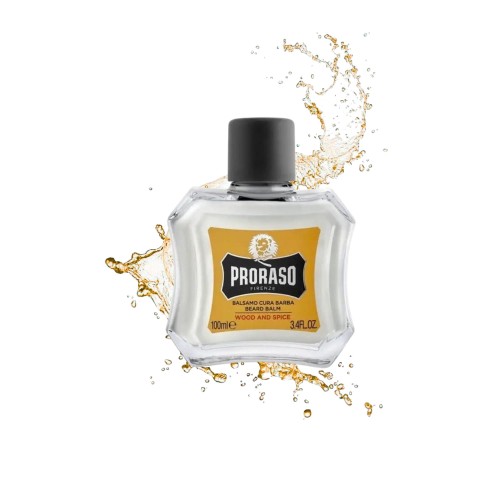 Proraso Balsam do brody Wood and Spice 100ml - żółta etykieta, przezroczysta butelka z czarnym korkiem, otoczona rozpryskującym się złotym płynem na białym tle.