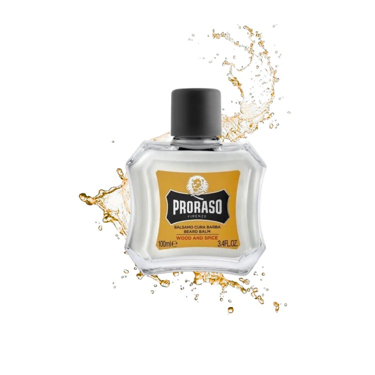 Proraso Balsam do brody Wood and Spice 100ml - żółta etykieta, przezroczysta butelka z czarnym korkiem, otoczona rozpryskującym się złotym płynem na białym tle.